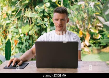 Konzentrierter junger Mann, der Laptop verwendet, erfolgreicher Freiberufler, der online am Computer in der modernen Küche sitzt Stockfoto