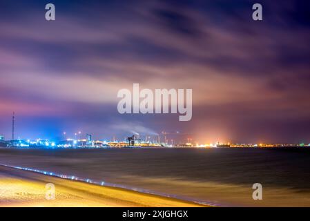 Langzeitbelichtung der Ölraffinerie San Roque vom Strand El Rinconcillo in der Bucht von Algeciras, Spanien, mit Hervorhebung der pulsierenden Lichter der Stadt und der Industrie Stockfoto