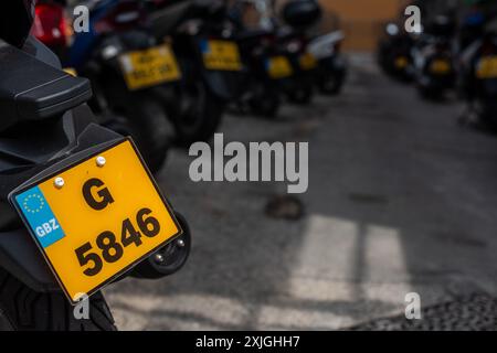 Nahaufnahme von Motorradkennzeichen mit Schwerpunkt auf einem in Gibraltar, Großbritannien. Mehrere Motorräder werden im Hintergrund geparkt. Stockfoto