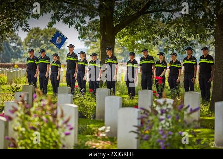 Groesbeek, Niederlande. Juli 2024. Die niederländische Polizei zeigt Respekt auf dem kanadischen Kriegsfriedhof. Auf dem Friedhof befinden sich die Gräber von 2.619 Soldaten, die im Zweiten Weltkrieg ums Leben kamen. Die Wanderer stehen vor dem Opferkreuz, einem Kreuz aus Portland-Stein mit einem Metallschwert auf der Oberseite. Dieses Jahr ist 80 Jahre her, dass in Groesbeek im Rahmen der Operation Market Garden ein großangelegter Luftangriff stattfand. Quelle: SOPA Images Limited/Alamy Live News Stockfoto