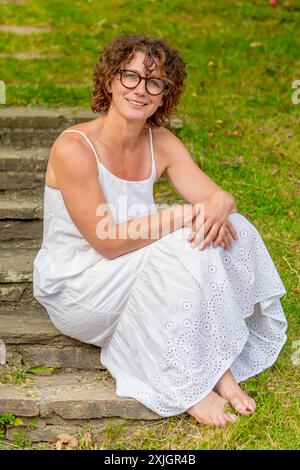 Frau in weißem Kleid, die auf Steinstufen sitzt Stockfoto