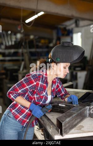 Erwachsene Frau schweißt Metallteile in der Werkstatt Stockfoto