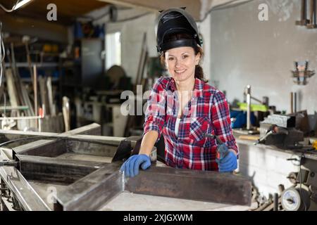 Erwachsene Schweißerin posiert in der Werkstatt Stockfoto