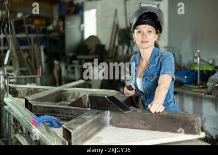 Erwachsene Schweißerin posiert in der Werkstatt Stockfoto