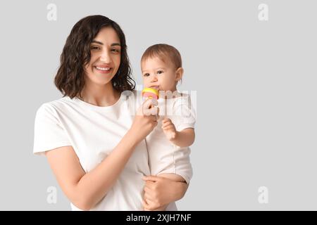 Mutter gibt ihrem kleinen Babyknabber Nahrung auf hellem Hintergrund Stockfoto