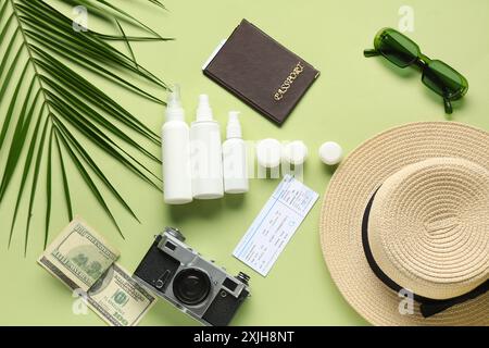 Komposition mit kosmetischem Reiseset, weiblichen Strandaccessoires, Ticket und Palmblatt auf grünem Hintergrund Stockfoto