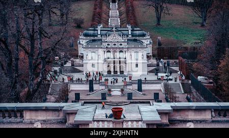 Deutschland - 07. November 2023: Ein großer weißer Palast befindet sich auf einer Reihe von Stufen, die von einem Innenhof hinauf führen, umgeben von einem üppigen Wald in Deutschland. Stockfoto