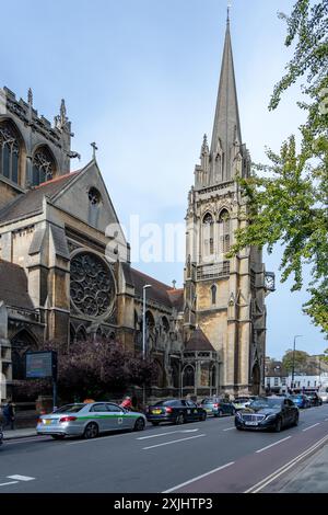 Cambridge, Großbritannien - 8. Oktober 2023 : Ein hoher, spitzer Kirchturm steht hoch vor einem blauen Himmel in Cambridge, Großbritannien. Die Kirche ist alt und reich mit einem l Stockfoto