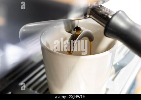 Kaffee in eine Kaffeetasse in einer Restaurant-Kaffeemaschine. Stockfoto