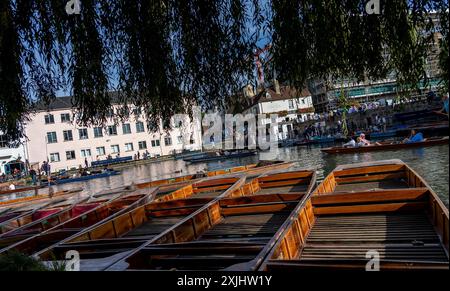 Cambridge, UK - 8. Oktober 2023 : zusammengebundene Holzpunzen, die auf dem Fluss Cam in Cambridge, Großbritannien, aufgereiht sind. Die Boote warten auf Touristen und Loc Stockfoto