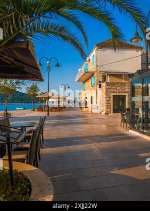 Primosten, Kroatien - Strandpromenade der Altstadt von Primosten an einem sonnigen Sommermorgen in Dalmatien mit Palmen, Restaurants, warmen Lichtern und blauem Meer Stockfoto