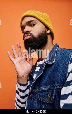 Afroamerikaner in stilvoller Kleidung und gelbem Hut, posiert vor einer lebendigen Kulisse. Stockfoto