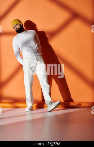 Ein modischer Afroamerikaner in einem weißen Outfit steht selbstbewusst vor einer lebendigen Wand. Stockfoto
