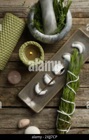 Flache Lagenkomposition mit Räucherstäbchen schwelend in Halter auf Holztisch Stockfoto