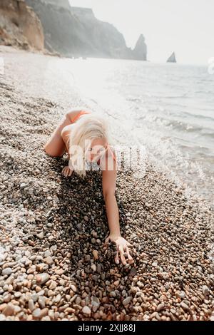 Die blonde Frau in Red Bikini spielt an einem Kieselstrand Stockfoto