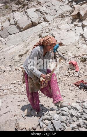 Hart arbeitende Frau bricht Steine mit einem Hammer, baut im Sommer eine Straße in Himachal Pradesh, Indien Stockfoto