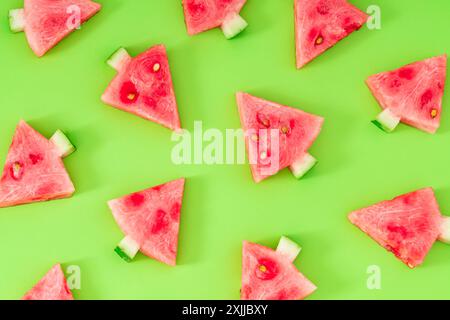 Kreative Musterkomposition mit Weihnachtsbäumen aus frischen Wassermelonenscheiben auf grünem Hintergrund. Minimales Weihnachts- oder Neujahrskonzept. Stockfoto