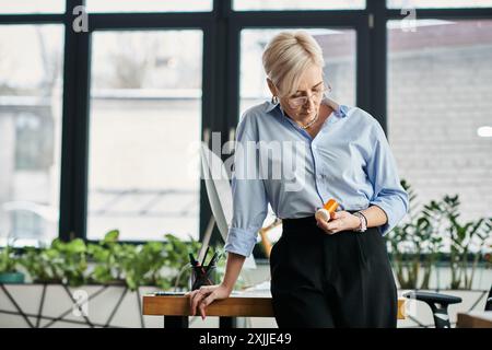 Eine Geschäftsfrau mittleren Alters mit kurzen Haaren steht selbstbewusst und hält Pillen aus der Menopause. Stockfoto