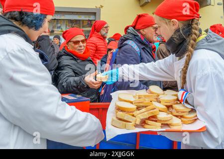 Ivrea, Italien - 19. Februar 2023: Menschen behandeln die Menge mit Essen, eine Tradition, die Teil des historischen Karnevals von Ivrea, Piemont, Norther ist Stockfoto