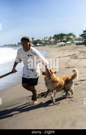 Mann spielt am Strand mit Retriever-Hund, rennt und täuscht herum. Stockfoto