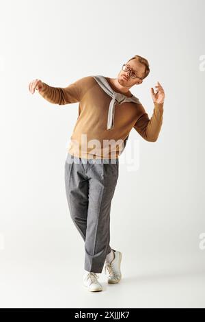 Gutaussehender Mann posiert aktiv in stilvollem braunem Hemd und grauer Hose. Stockfoto