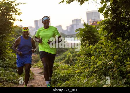 Zwei Freunde laufen auf Trails mit der Skyline der Stadt im Hintergrund. Stockfoto