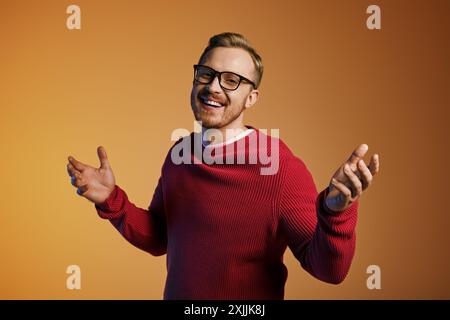 Hübscher Mann mit Brille und rotem Pullover, der selbstbewusst posiert. Stockfoto