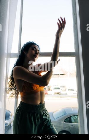 Frau tanzt anmutig vor einem Fenster Stockfoto