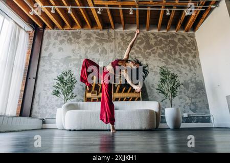 Frau tanzt energisch in einem Loft mit rotem Outfit Stockfoto