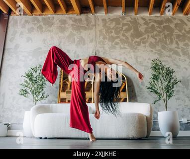 Frau tanzt energisch in einem Loft mit rotem Outfit Stockfoto