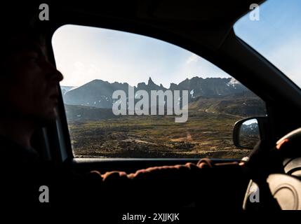 Mann hinter dem Rad, Blick vom Autofenster auf die Berge Stockfoto