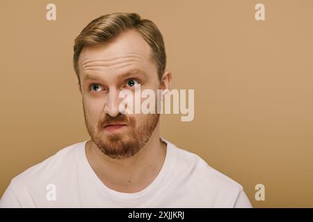 Ein gutaussehender Mann in einem weißen T-Shirt schlägt eine dynamische Pose. Stockfoto