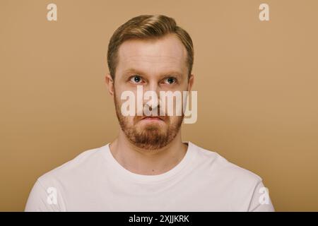 Ein stilvoller Mann mit Bart posiert selbstbewusst in einem weißen Hemd. Stockfoto