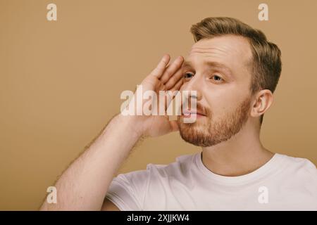 Ein stilvoll gekleideter Mann mit Bart legt seine Hand auf sein Gesicht und denkt tief nach. Stockfoto