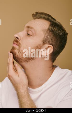 Ein stilvoller Mann mit Bart und weißem Hemd posiert selbstbewusst. Stockfoto