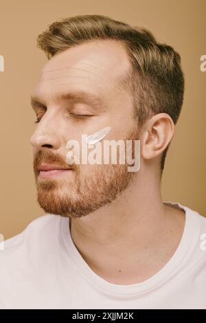 Ein stilvoller Mann, der eine Gesichtscreme trägt, entspannt sich während seiner Hautpflege. Stockfoto