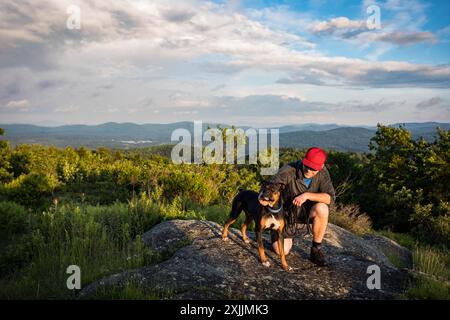 Mann streichelt seinen Hund an einem malerischen Aussichtspunkt in New Hampshire Stockfoto