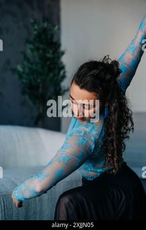 Frau in blauem Spitzenoberteil posiert anmutig in einem stilvollen Studio Stockfoto