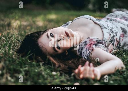 Schöne junge Frau, die auf dem Gras liegt, ausdrucksvoller Blick Stockfoto