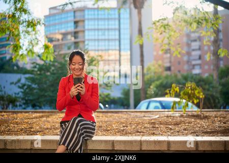 Asiatische Geschäftsfrau, die im Stadtpark ihr Smartphone benutzt Stockfoto