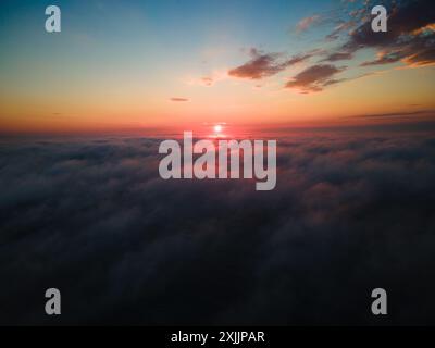 Die aufgehende Sonne über niedrigen Wolken während eines Sommersonnenaufgangs Stockfoto