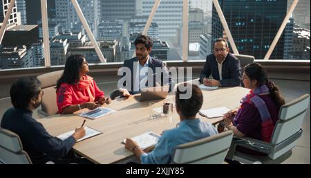 Hochauflösende Aufnahmen eines diversen Teams von professionellen südasiatischen Geschäftsleuten in einem Büro-Konferenzraum. Kreativteam sitzt hinter einem Tisch und diskutiert die Marketingstrategie für soziale Medien Stockfoto