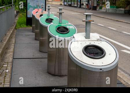 Reihe von Recyclingbehältern für Glas in verschiedenen Farben neben einer Straße auf einem Bürgersteig. Das Konzept der Umweltfreundlichkeit und Fürsorge. Stockfoto