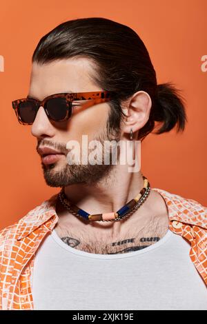 Ein bärtiger Mann in Sonnenbrille und Halskette strahlt Vertrauen und Stil aus. Stockfoto