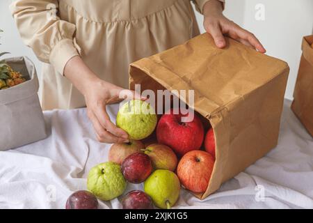 Abgeschnittene Aufnahme einer Frau, die Papiertüte mit frischen Früchten im Bett hält Stockfoto