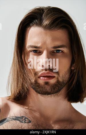 Schöner Mann mit langen Haaren und Bart, in trendiger Kleidung gekleidet. Stockfoto