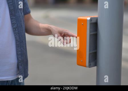 Nahaufnahme eines Mannes, der an einer Ampel an einer Fußgängerüberquerung einen Signalknopf drückt. Sicheres Überqueren der Straße durch grünes Ampelkonzept. Stockfoto