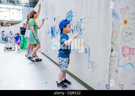 London, Großbritannien. Juli 2024. UNIQLO Tate Play: Oscar Murillo: Der überflutete Garten in Tate Modern. Murillo lädt Besucher aller Altersgruppen ein, sich in der Turbine Hall auf einem mehrschichtigen Gemälde zu präzisieren, um sie dazu zu ermutigen, Wasser und Wellen über Leinwände zu malen und so ein riesiges Gemeinschaftsbild zu schaffen. Das Werk ist von Claude Monets Wasserlilien inspiriert und baut auf Murillos Serie von Surge-Werken auf. Guy Bell/Alamy Live News Stockfoto