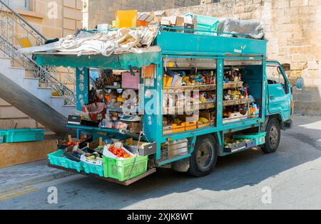 Ein lebendiger mobiler Supermarkt-Truck auf der Straße, gefüllt mit frischen Produkten und verschiedenen Waren. Konzept der Bequemlichkeit und der lokalen Einkaufsmöglichkeiten. Stockfoto