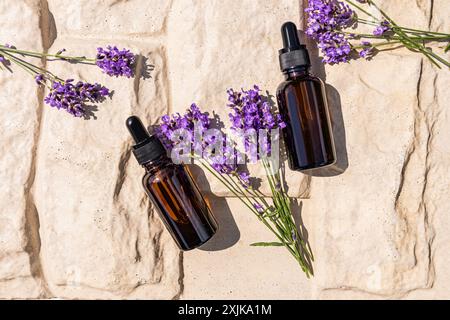 Zwei Kosmetiktropfflaschen mit einem natürlichen Gesichts- und Körperpflegeprodukt auf Basis von Lavendelöl. Bio-Kosmetik. Spa. Beigefarbener Hintergrund Stockfoto